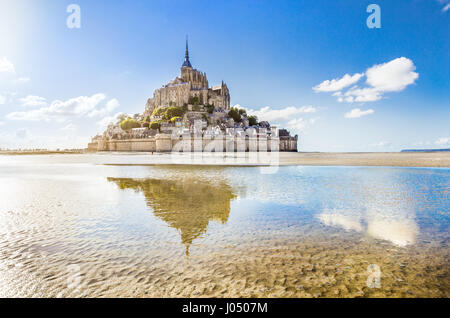 Panoramic view of famous Le Mont Saint-Michel tidal island on a sunny day with blue sky and clouds, Normandy, northern France