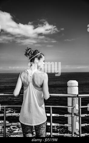 Look Good, Feel great! Seen from behind young woman in fitness outfit looking aside at the embankment Stock Photo
