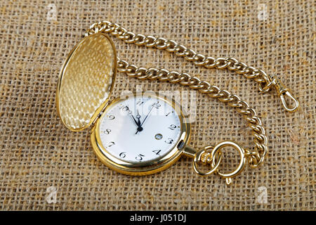 old golden pocket watch on burlap background Stock Photo