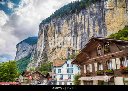 Beautiful view of the historic town of Lauterbrunnen with famous Staubbach Falls in the background on a sunny day with clouds in summer, Switzerland Stock Photo