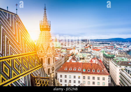 Aerial view over the historical rooftops of Vienna from the north tower of famous St. Stephen's Cathedral in beautiful golden evening light at sunset  Stock Photo