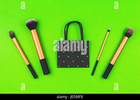 Make up brushes with black polka dot paper shopping bag on greenery background Stock Photo