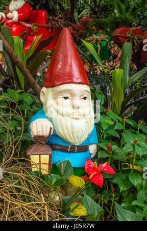Garden gnome surrounded by plants and trees Stock Photo