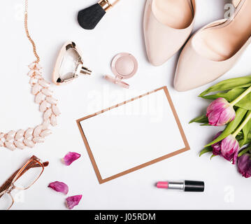 Woman's accessories of beige color, pink tulips and blank paper on white table, top view. Stock Photo