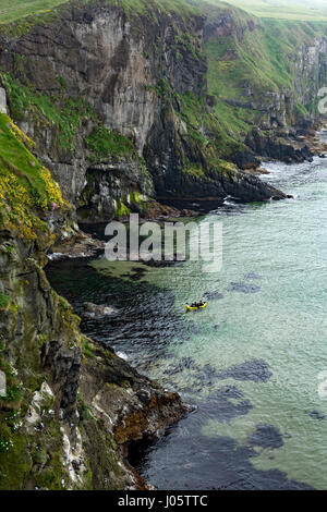 An inflatable canoe below cliffs near the Carrick-a-Rede rope bridge, Causeway Coast, County Antrim, Northern Ireland, UK Stock Photo