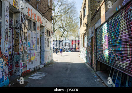An alleyway leading off Brick Lane in east London is covered with street art and graffiti. Stock Photo