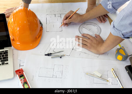 Interior designer discussing data and digital tablet and computer laptop with business document and graphics design diagram on wooden desk as concept Stock Photo