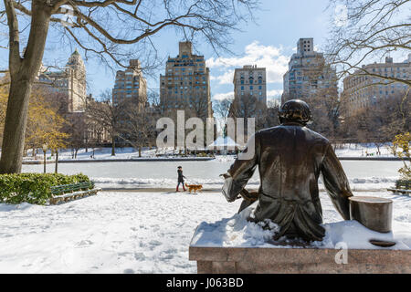 Hans Christian Andersen statue with woman walking dog in the snow Stock Photo