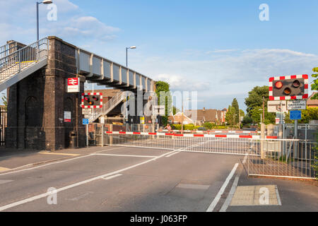 Road with level crossing barriers lowered, Attenborough Railway Station, Nottinghamshire, England, UK Stock Photo