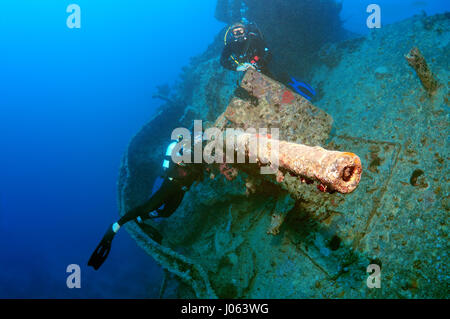 Divers inspecting an anti-aircraft gun. EERIE underwater pictures show inside the wreckage of the sunken British World War Two ship SS Thistlegorm on the seventy-fifth anniversary of her sinking. The series of images show the rusted remains of the merchant navy ship’s cargo which includes motorbikes, army trucks and an aircraft propeller. Other pictures show how sea life have been inhabiting the wreckage. Stock Photo