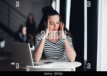 Tired minded woman thinking about way to complete a task. Beatiful female having a headache during a break in a cafe. Stock Photo