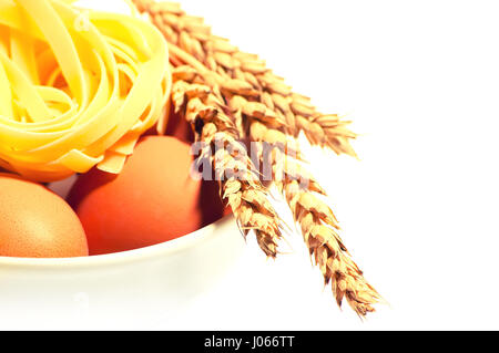 Chicken eggs with wheat spikelets and pasta isolated on white background toned Stock Photo