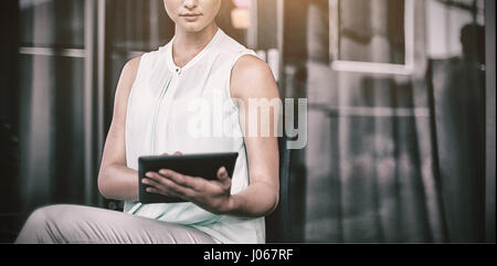 Businesswoman using digital tablet while sitting on chair in office Stock Photo
