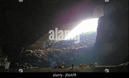 SON DOONG, VIETNAM: EYE-OPENING images showing tourists venturing and camping inside the world’s largest cave have emerged. The awesome pictures show people pitching tents to camp the night inside the two-and-a-half mile long Hang Son Doong, central Vietnam and looking like matchstick characters as they enter the cave’s mouth -  where inside it is 800-foot tall. Other images show a river flowing into the cave and tourists trekking alongside the stream. The stunning photographs were taken by retired civil engineer Douglas Knuth (65) from Woodstock, Illinois, USA at Son Doong, Vietnam. To take h Stock Photo