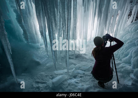 ALBERTA, CANADA: STUNNING images showing women having fun inside sparkling frozen Canadian waterfalls have been revealed by one British expat who lives there. The series of shots show the women sitting directly below giant icicles and walking through what looks like a maze of icicles that touch the frozen ground. Other shots show people taking pictures and admiring the glistening ice formations. One super fun shot shows a woman sliding down an icy slope on her bottom with her arms out wide. The spectacular photographs were taken at Icefields Parkway, near Banff in Alberta, Canada by photograph Stock Photo