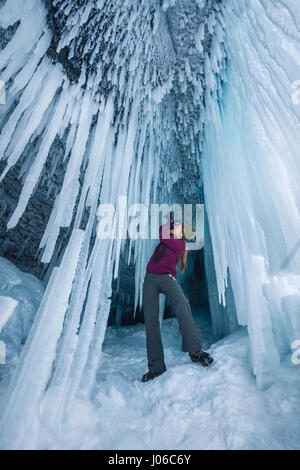 ALBERTA, CANADA: STUNNING images showing women having fun inside sparkling frozen Canadian waterfalls have been revealed by one British expat who lives there. The series of shots show the women sitting directly below giant icicles and walking through what looks like a maze of icicles that touch the frozen ground. Other shots show people taking pictures and admiring the glistening ice formations. One super fun shot shows a woman sliding down an icy slope on her bottom with her arms out wide. The spectacular photographs were taken at Icefields Parkway, near Banff in Alberta, Canada by photograph Stock Photo