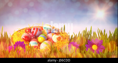 Multi colored easter eggs in wicker basket against white clouds under blue sky Stock Photo