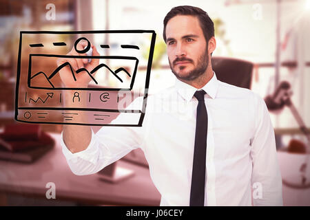 Focused businessman writing with marker against blurry picture of computer on desk Stock Photo