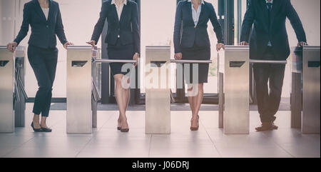 Businesspeople standing at turnstile gate in office Stock Photo