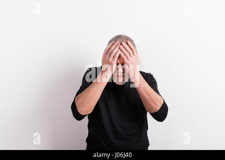 Upset senior man with headache, holding his head, studio shot. Stock Photo