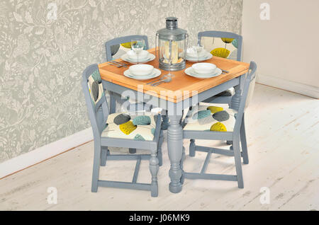 Dining table with chairs, plates, bowls and cutlery. Shabby chic dining room interior. Stock Photo