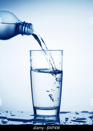 Water flowing from bottle into a glass toned in blue Stock Photo