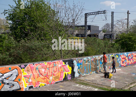 Father and son spraying a wall with graffiti in a playground in Tottenham,London,UK Stock Photo