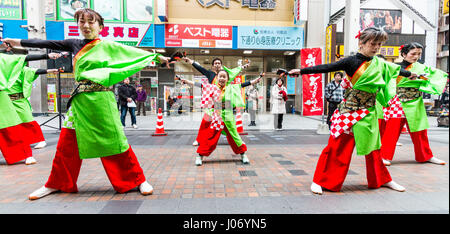 Japan, Kumamoto, Hinokuni Yosakoi dance festival. Team with child, girl, dancing in the centre, all in red and green yukata.