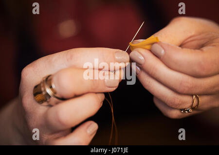 A woman using a needle threaded with cotton thread. Stock Photo