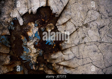 Close up detail of a painted metal surface which is broken up and rusty, showing parts of different colored paint. Stock Photo