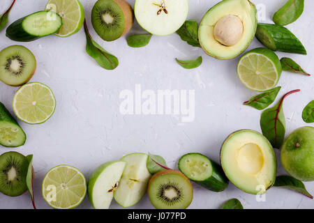 Frame of green vegetables and fruits over light gray plaster  table, food background with free space for text Stock Photo