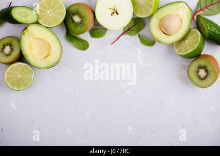 Frame of green vegetables and fruits over light gray plaster  table, food background with free space for text Stock Photo