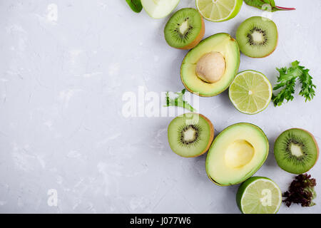 Frame of green vegetables and fruits over light gray plaster  table, food background with free space for text Stock Photo