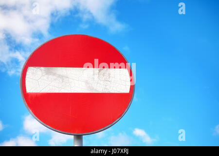 Do not enter weathered round sign on a metal post against blue cloudy sky, space for text. Stock Photo