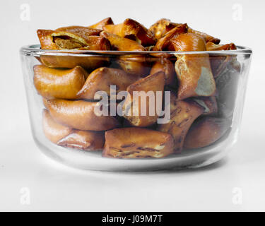 Closeup on a portion of unsalted peanut butter pretzels in glass bowl on white background viewed from the side Stock Photo