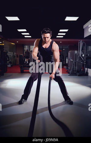 Man is doing exercises  working out with a rope in the gym Stock Photo