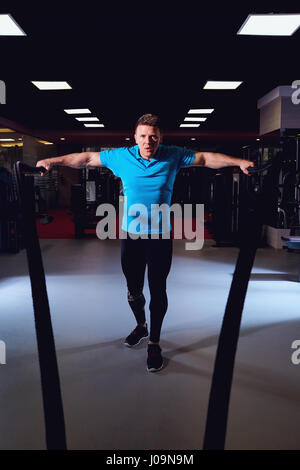 Man is doing exercises  working out with a rope in the gym Stock Photo