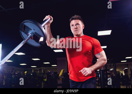 Athletic male athlete doing exercises with a barbell in the gym Stock Photo