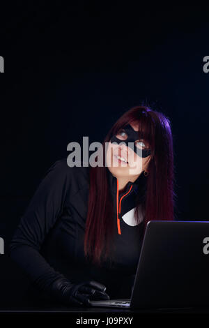 Hacker in mask with laptop Stock Photo