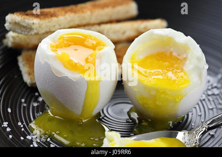 Two soft boiled eggs with toast soldiers in the background. Extreme shallow depth of field with selective focus. Stock Photo