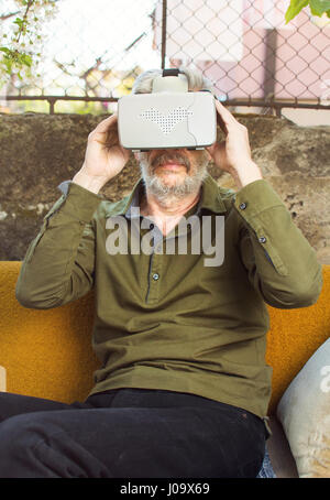 Senior man using virtual reality goggles in the backyard Stock Photo