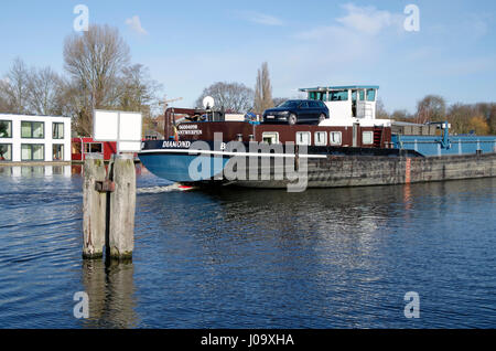 Bulk carrier barge passing modern house boats on Schinkel canal in Amsterdam-Zuid, Netherlands Stock Photo