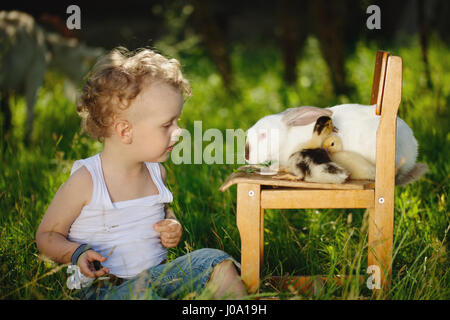 boy with yellow duckling and rabbit in summer village Stock Photo