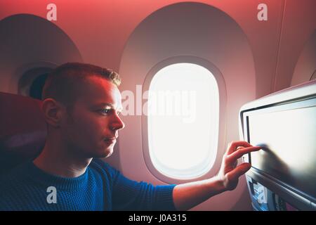 Comfortable traveling by airplane. Young passenger enjoying his journey inside an airplane. Stock Photo