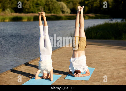 couple making yoga headstand on mat outdoors Stock Photo