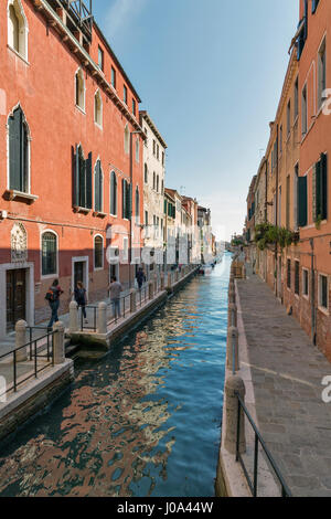 VENICE, ITALY - SEPTEMBER 23, 2016: People walk along narrow canal Rio della Fornace in Dorsoduro district. Venice is situated across 117 islands that Stock Photo