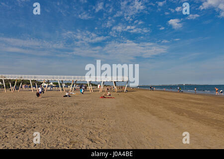 LIDO, ITALY - SEPTEMBER 23, 2016: Unrecognized people have a rest and walk along sandy beach. Lido is an island known for its 11 km long sandbar. Veni Stock Photo