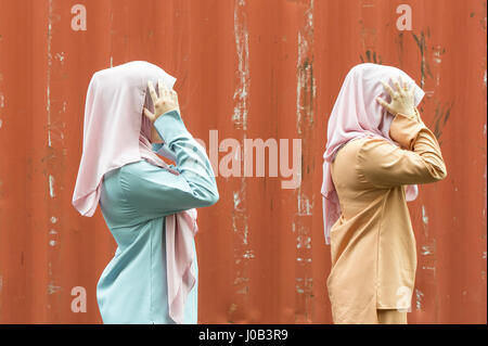 Two malaysian young lady in modern attire reacting happily with authentic malaysian smile at outdoor location. Stock Photo