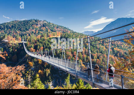 Tourists on the suspension bridge called Highline 179 framed by colorful woods in autumn, Ehrenberg Castle, Reutte, Austria Stock Photo
