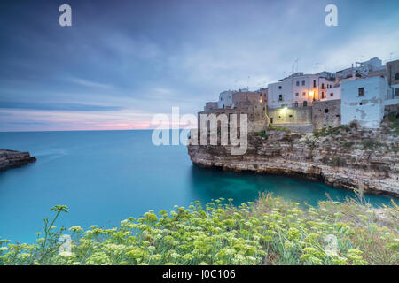 Turquoise sea at sunrise framed by the old town perched on the rocks, Polignano a Mare, Province of Bari, Apulia, Italy Stock Photo